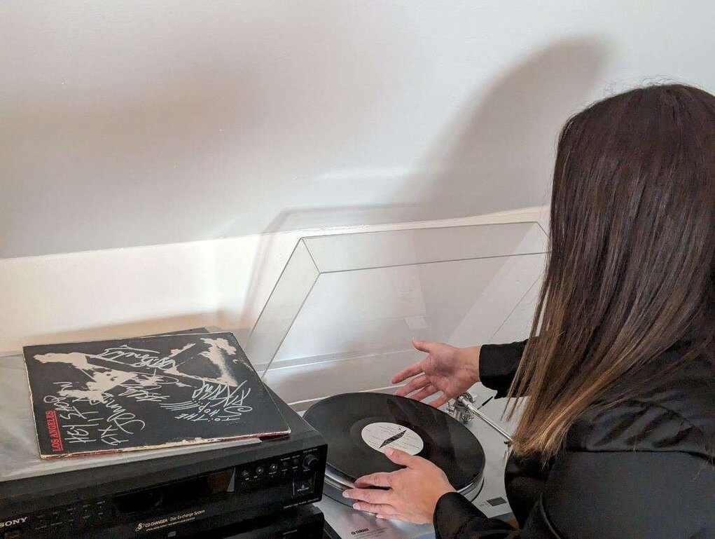 Alana Boscan putting a vinyl disc in a vinyl player.